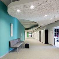 Langer Gang mit Sitzbank, Abgehängte Decke mit Spots und einfärbig-bunten Wänden