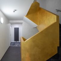 Treppenaufgang mit schwarzen Treppen und einem gelben Geländer