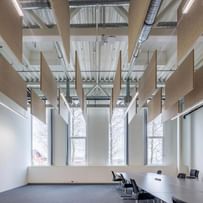 Lichtdurchfluteter Konferenzraum mit schwebenden Hanfpaneelen unter der Decke