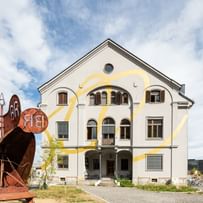 Eingangsbereich des Gebäudes mit davorstehenden rostigen Stahlkonstruktion