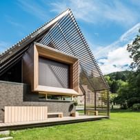 Außenansicht eines modernen Passivhauses mit Holzfassade in natürlichem Grauton, großen Fensterflächen und flach geneigtem Dach, aufgenommen bei Tageslicht im Rahmen der NÖ Landesausstellung in Neubruck, Scheibbs.