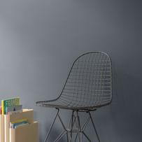 Schwarzer Drahtstuhl vor einer grauen Wand