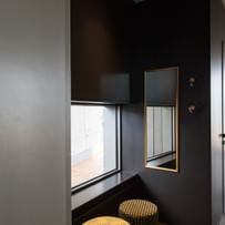 Schwarze Ecke im Restaurant mit Spiegel und goldenen Sitzhockern