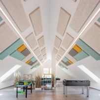 Dachzimmer mit bunten Hanfakustik-Platten und Tischkicker