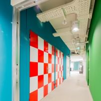 Langer Gang mit industriellen Belüftungsanlage an der Decke und einfärbig-bunten Wänden