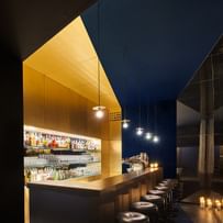 Bar mit Barhockern und Auswahl an alkoholischen Getränken im Regal