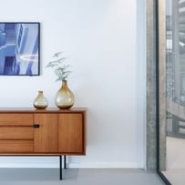 Stilvolle Sitzecke mit sanftgrauem Boden und Mid-Century-Möbelstück für warme Klarheit