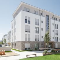 Blick auf das gesamte Gebäude mit Grünfläche und Sitzmöglichkeiten