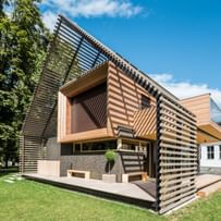 Außenansicht eines modernen Passivhauses mit Holzfassade in natürlichem Grauton, großen Fensterflächen und flach geneigtem Dach, aufgenommen bei Tageslicht im Rahmen der NÖ Landesausstellung in Neubruck, Scheibbs.