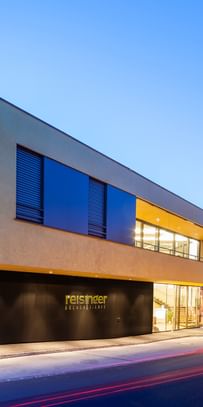 Modernes Gebäude der Bäckerei Reisinger in Gutau mit großzügigen Glasfronten und einer Fassadengestaltung mit CapaGold.