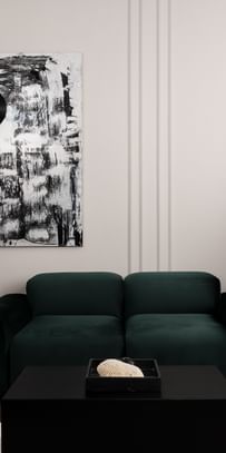 Eleganter Loungebereich einer Executive Suite im „The Amauris“ Wien mit tiefgrünem Samtsofa, großem abstraktem Schwarz-Weiß-Gemälde, skulpturaler schwarzer Stehleuchte, schwarzem Marmorsockel und bodenlangen beigefarbenen Vorhängen.