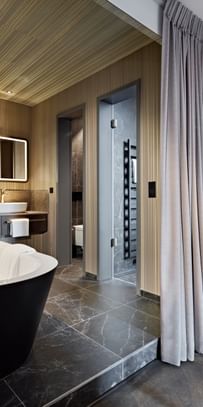 Schwarze Badewanne inmitten eines Hotel-Badezimmers