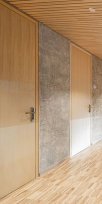 Flur einer Volkshochschule. Entlang des Flurs sind mehrere Türen aus Holz, die in weitere Räume führen.