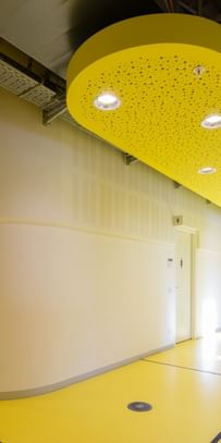 Gang mit gelbem Boden, weiße Wände und industrieller Belüftung an der Decke