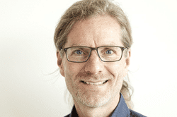 Portrait von Guido Kuphal: Ein Mann mit blonden langen Haaren und einer rechteckigen schwarzen Brille
