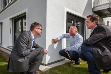 Drei Männer begutachten gemeinsam eine weiße Fassade – Fokus, Fachwissen und Teamgeist