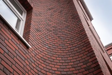 Backsteinfassade in leuchtendem Rotton mit schwungvoller Wölbung – kraftvoll und lebendig