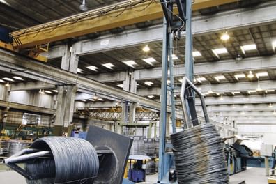 Eine industrielle Umgebung mit einer großen Maschine, die Drahtrollen verarbeitet.
