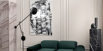 Moderner Sitzbereich im „The Amauris“ Wien mit grünem Samtsofa, hellem Teppich, abstrakter Wandkunst, skulpturaler Stehleuchte, schwarzem Couchtisch, kariertem Sessel und auffälligem, geschwungenen Deckenleuchten-Element.