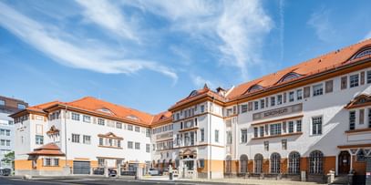 Detailreiche Jugendstilfassade des Dorotheum Linz mit aufwendig verzierten Fenstern, geometrischen Ornamenten und markanten orangefarbenen Zierelementen, restauriert mit Histolith-Farben