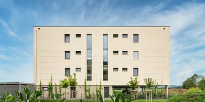 Außenansicht des Gebäudes mit grüner Rasenfläche vor dem Gebäude