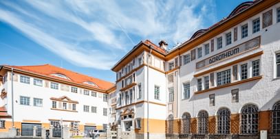 Detailreiche Jugendstilfassade des Dorotheum Linz mit aufwendig verzierten Fenstern, geometrischen Ornamenten und markanten orangefarbenen Zierelementen, restauriert mit Histolith-Farben