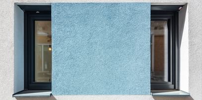 Schmale hohe Fenster mit türkiser Fassade