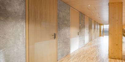 Flur einer Volkshochschule. Entlang des Flurs sind mehrere Türen aus Holz, die in weitere Räume führen.