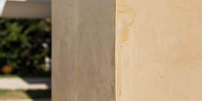 Wohnanlage in der Robert-Stolz-Straße in Linz. Ein modernes, mehrstöckiges Wohngebäude mit hellen Fassaden und zahlreichen Balkonen. Große Fenster sorgen für viel Tageslicht. Vor dem Gebäude stehen Autos auf einer ruhig wirkenden Straße, eingerahmt von gepflegten Grünflächen und Bäumen.