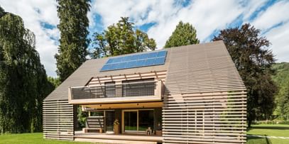 Außenansicht eines modernen Passivhauses mit Holzfassade in natürlichem Grauton, großen Fensterflächen und flach geneigtem Dach, aufgenommen bei Tageslicht im Rahmen der NÖ Landesausstellung in Neubruck, Scheibbs.