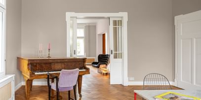 Klavierzimmer mit braunem Klavier und lila Sessel