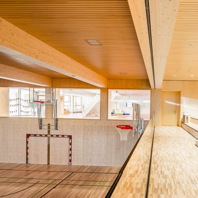 Sporthalle einer Volkshochschule mit einem Fußballtor, einem Basketballkorb und einer Tribüne aus Holz.