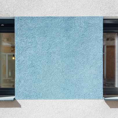 Schmale hohe Fenster mit türkiser Fassade
