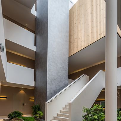 Lichtdurchflutetes Atrium mit Holz, Naturstein und modernem Treppenaufgang