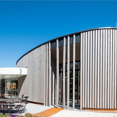 Holzlamellen in organischer Rundung – harmonischer Dialog aus Natur und Architektur