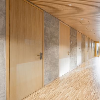 Flur einer Volkshochschule. Entlang des Flurs sind mehrere Türen aus Holz, die in weitere Räume führen.