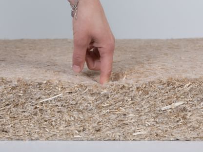 Eine Hand drückt prüfend in eine weiche Dämmplatte aus natürlichem Hanfmaterial