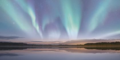 Polarlichter tanzen über stillem See und verschmelzen mit der Dämmerung