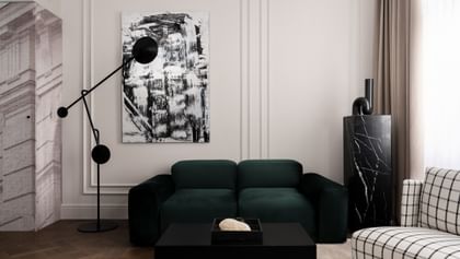 Eleganter Loungebereich einer Executive Suite im „The Amauris“ Wien mit tiefgrünem Samtsofa, großem abstraktem Schwarz-Weiß-Gemälde, skulpturaler schwarzer Stehleuchte, schwarzem Marmorsockel und bodenlangen beigefarbenen Vorhängen.