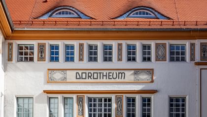 Detailreiche Jugendstilfassade des Dorotheum Linz mit aufwendig verzierten Fenstern, geometrischen Ornamenten und markanten orangefarbenen Zierelementen, restauriert mit Histolith-Farben