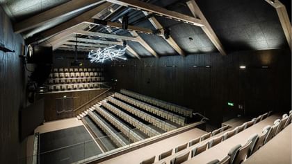 Modernes Theater mit Holztragwerk und futuristischer Lichtskulptur unter dem Dach