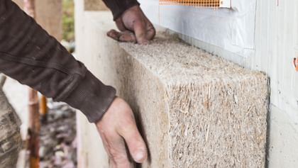 Hände bringen Hanfdämmplatte an – natürlicher Schutz für warme Innenräume