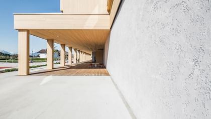 Gebäude mit Wänden in Betonoptik sowie einer hellen Holzverkleidung.