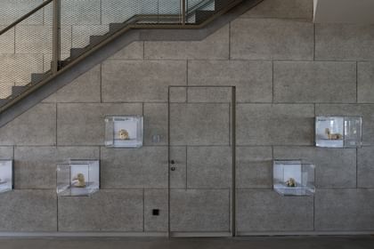 Wände aus Stahlbetonhalbfertigteilen mit Treppe im Hintergrund und an der Wand hängende kleine Glasvitrinen, die jeweils ein ausgestelltes Tiermodell enthalten