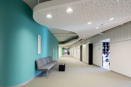 Langer Gang mit Sitzbank, Abgehängte Decke mit Spots und einfärbig-bunten Wänden