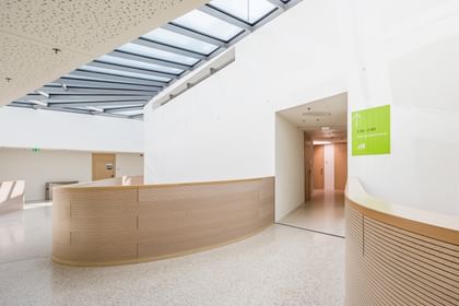 Moderner Innenraum mit Holzbrüstung der Anton Bruckner Privatuniversität Linz mit klaren Linien, großflächigen Dachfestern und hellen Wandflächen,