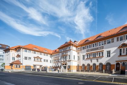 Detailreiche Jugendstilfassade des Dorotheum Linz mit aufwendig verzierten Fenstern, geometrischen Ornamenten und markanten orangefarbenen Zierelementen, restauriert mit Histolith-Farben