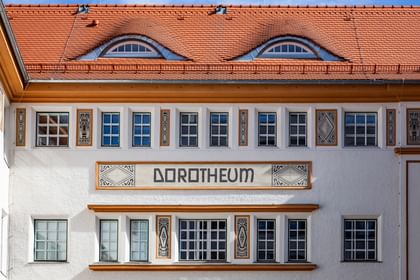 Detailreiche Jugendstilfassade des Dorotheum Linz mit aufwendig verzierten Fenstern, geometrischen Ornamenten und markanten orangefarbenen Zierelementen, restauriert mit Histolith-Farben