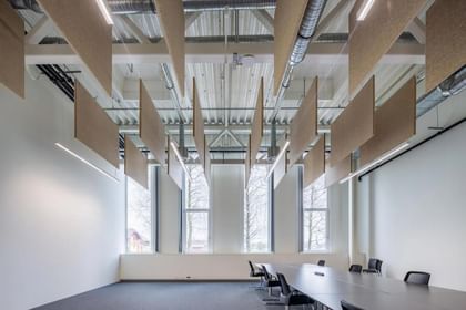Lichtdurchfluteter Konferenzraum mit schwebenden Hanfpaneelen unter der Decke