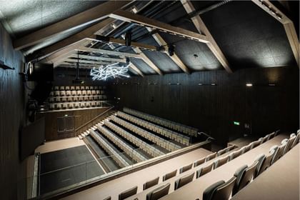 Modernes Theater mit Holztragwerk und futuristischer Lichtskulptur unter dem Dach